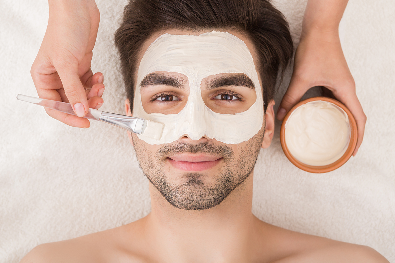 Unshaven man having facial mask in spa salon