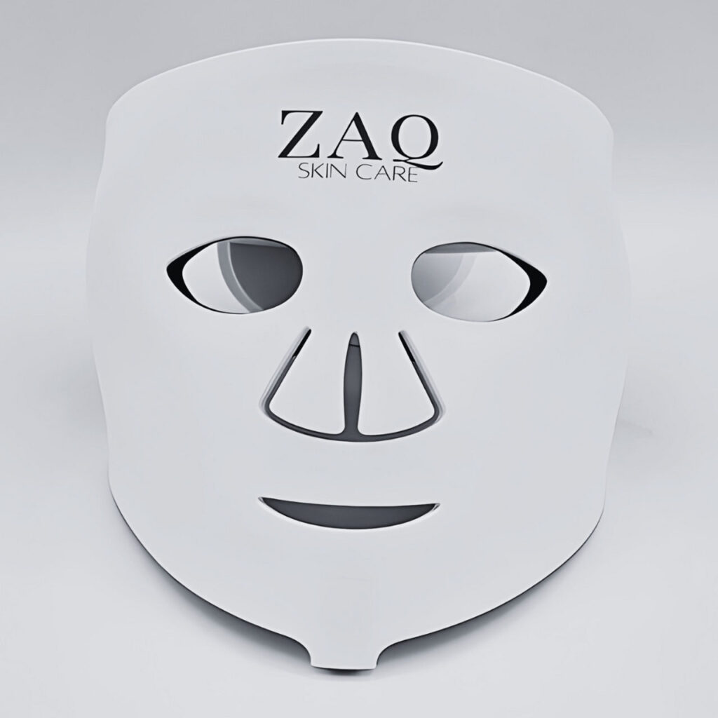 A white LED light face mask with "ZAQ Skin Care" printed at the top, featuring cutouts for the eyes, nose, and mouth, placed against a plain background.